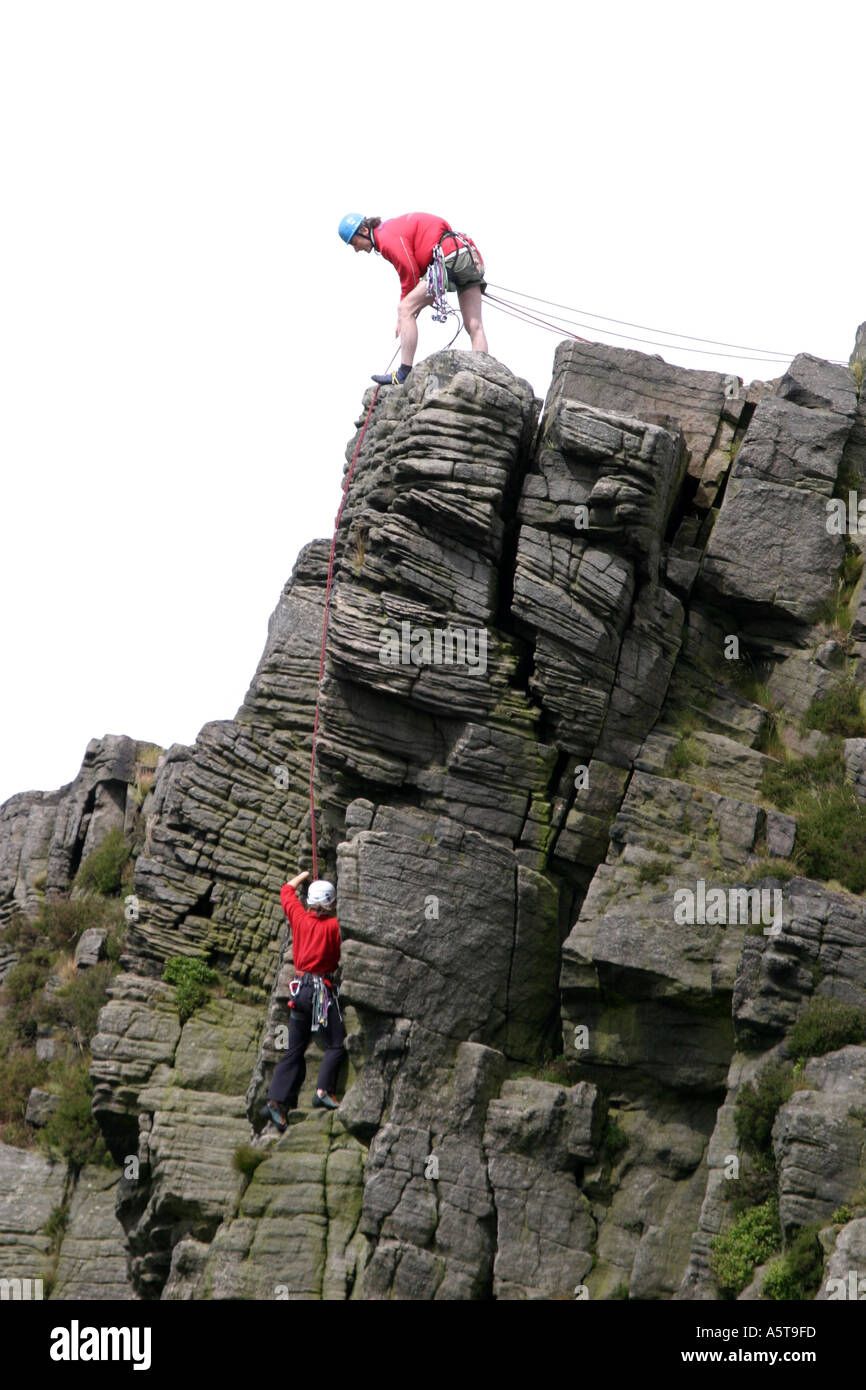 Alpinistes sur Windgather rochers sur le côté est du Peak District, Derbyshire, Angleterre. L'homme au haut des rochers est l'assurage d'un grimpeur sur le chemin vers le haut. Banque D'Images