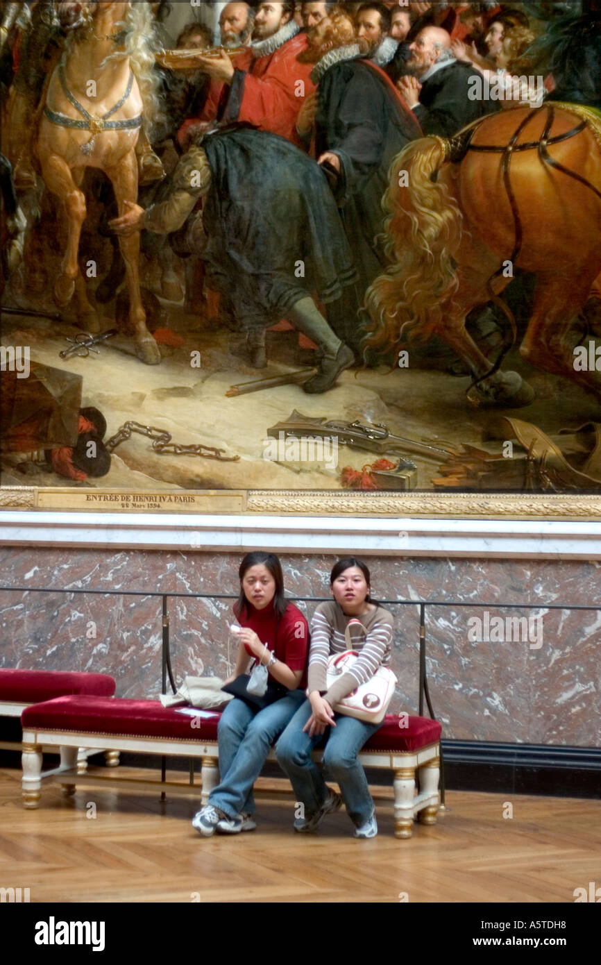 Deux femmes orientales s'asseoir sur un banc en velours rouge sous une immense toile représentant le roi de France Henri IV dans Paris Banque D'Images