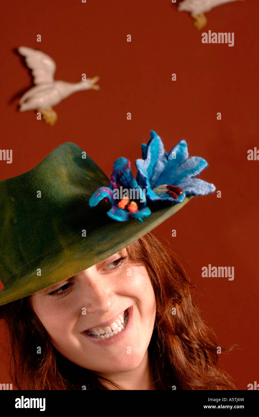 Un sourire heureux jeune femme portant des fleurs en feutre sur son chapeau. Photo par Jim Holden. Banque D'Images