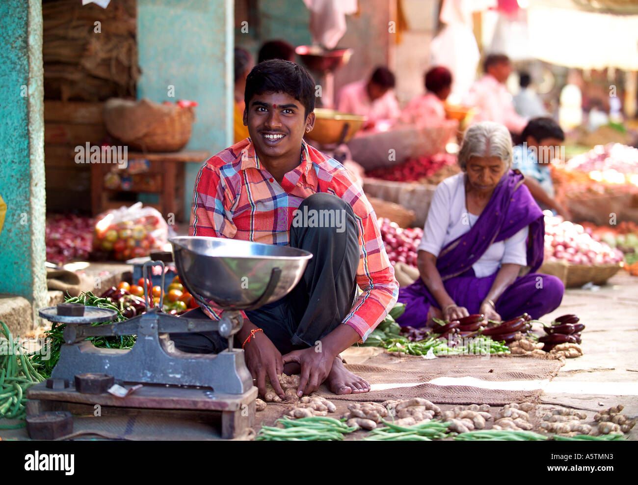 Jeune garçon riant la vente de légumes, fruits et légumes du marché Devaraja, Mysore, Inde. Banque D'Images