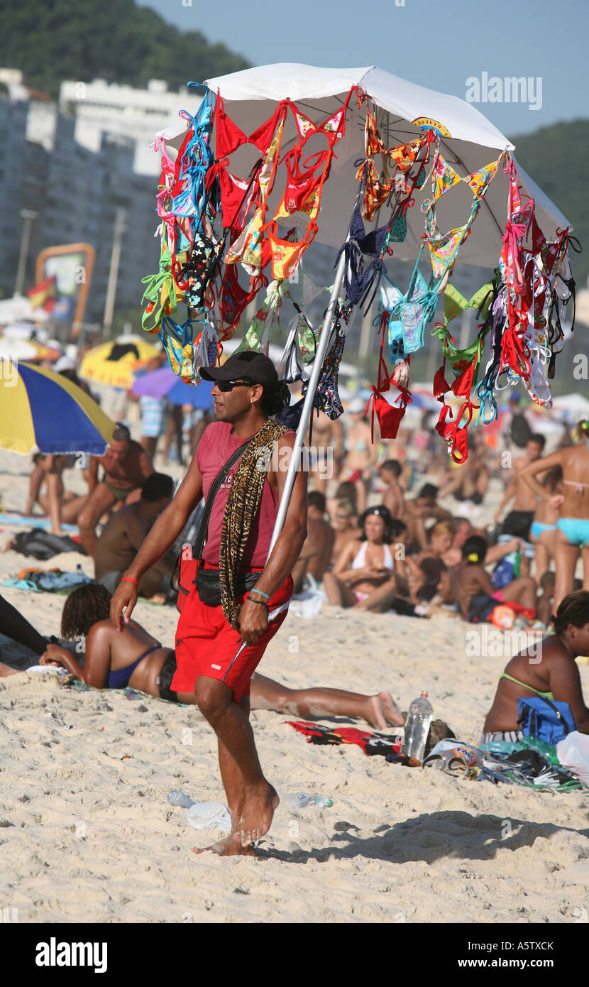 Portrait de l'homme vente de Fun bikinis suspendu à un parapluie, la plage de Copacabana, Rio de Janeiro, Brésil Banque D'Images