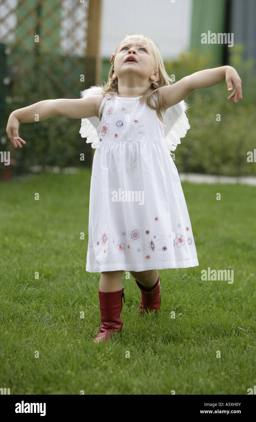 Angle peu Girl standing in garden imitant le vol Banque D'Images