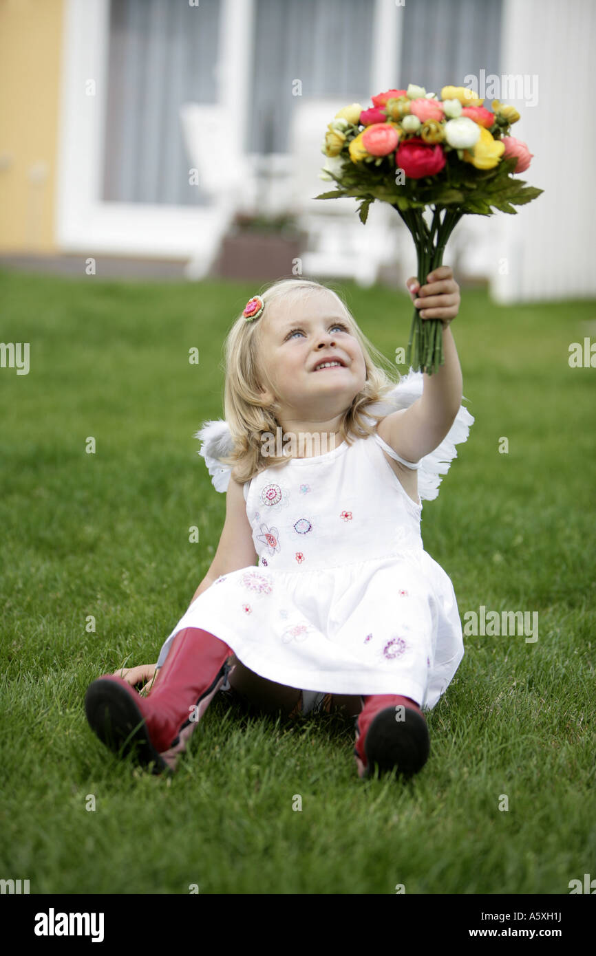 Girl sitting on ground holding bunch of flowers Banque D'Images