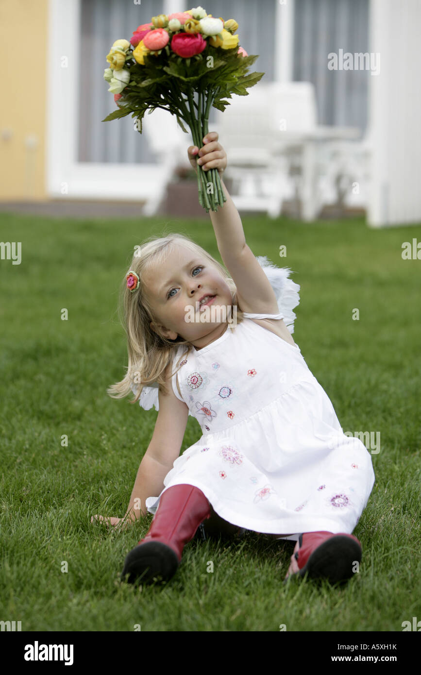 Girl sitting on ground holding bunch of flowers Banque D'Images