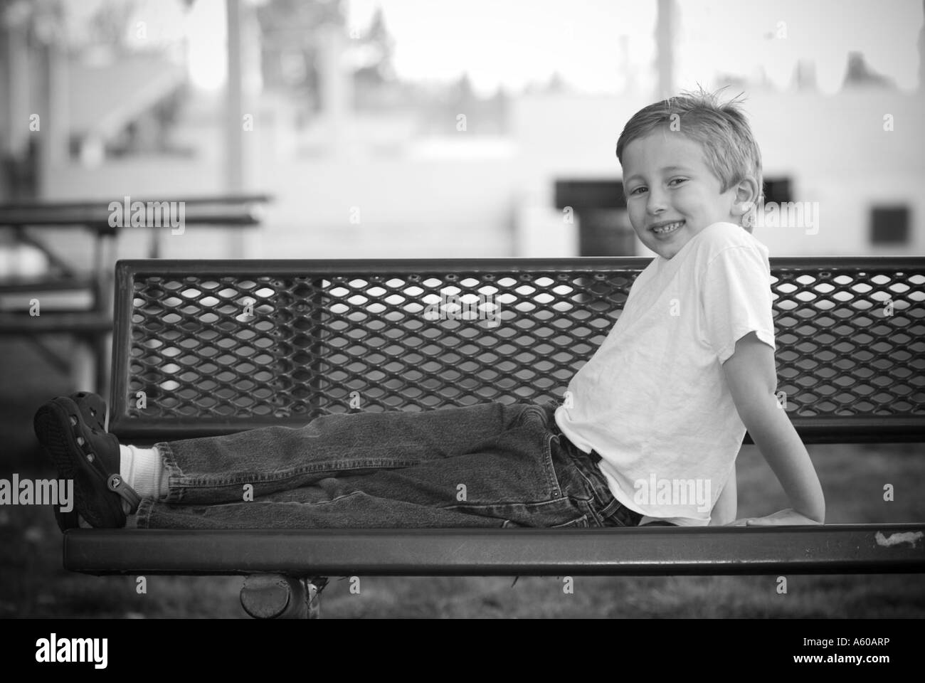 Cute kid sur un banc de parc Banque D'Images