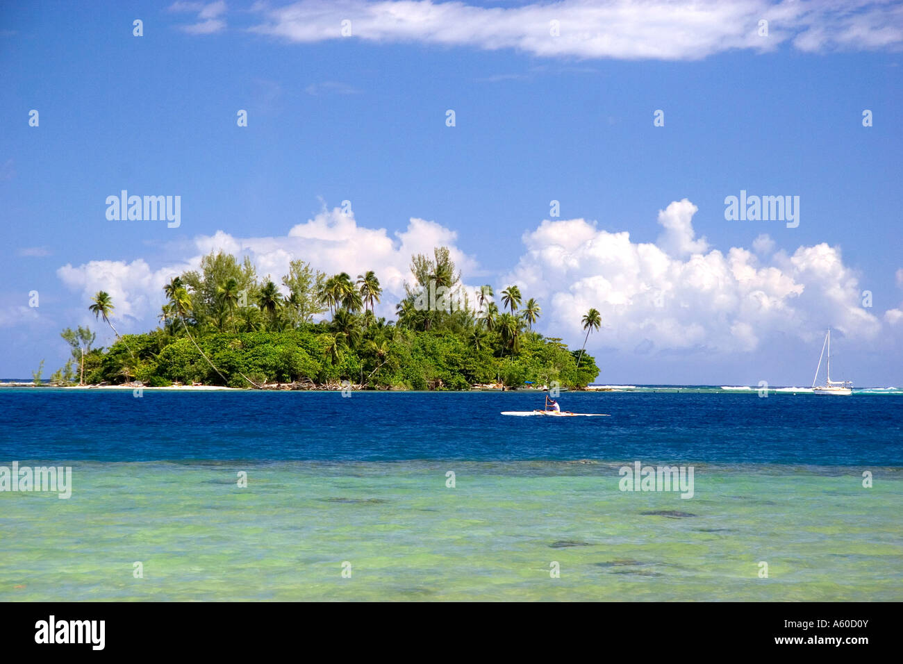 Petite île appelée un motu pirogue et d'un voilier au large de l'île de Moorea Banque D'Images