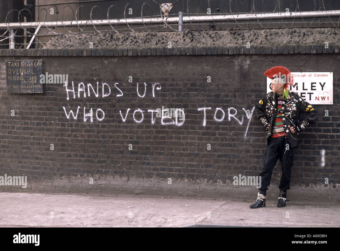 Punk debout devant mur de graffiti disant haut les mains qui ont voté Tory Banque D'Images