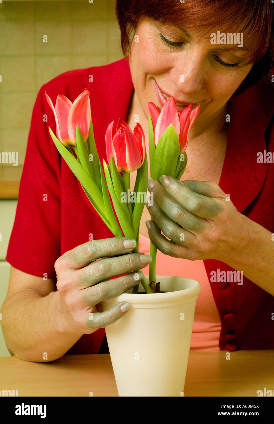 Femme avec les doigts verts détient fleurs Banque D'Images
