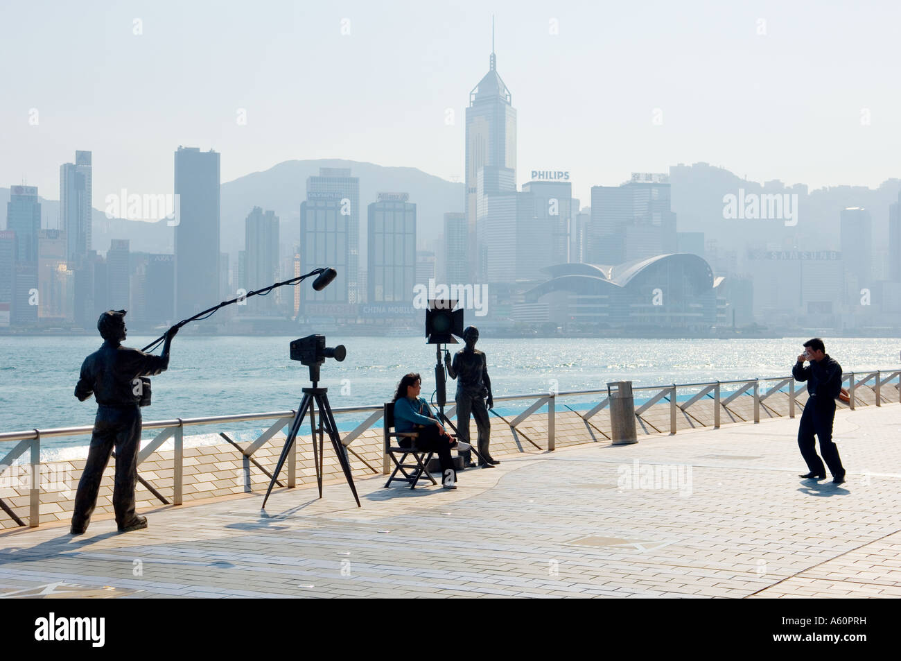 Les touristes et les statues de cinéma avec l'île de Hong Kong, le Port Victoria derrière. Sur l'Avenue of Stars, promenade, Kowloon, Chine Banque D'Images