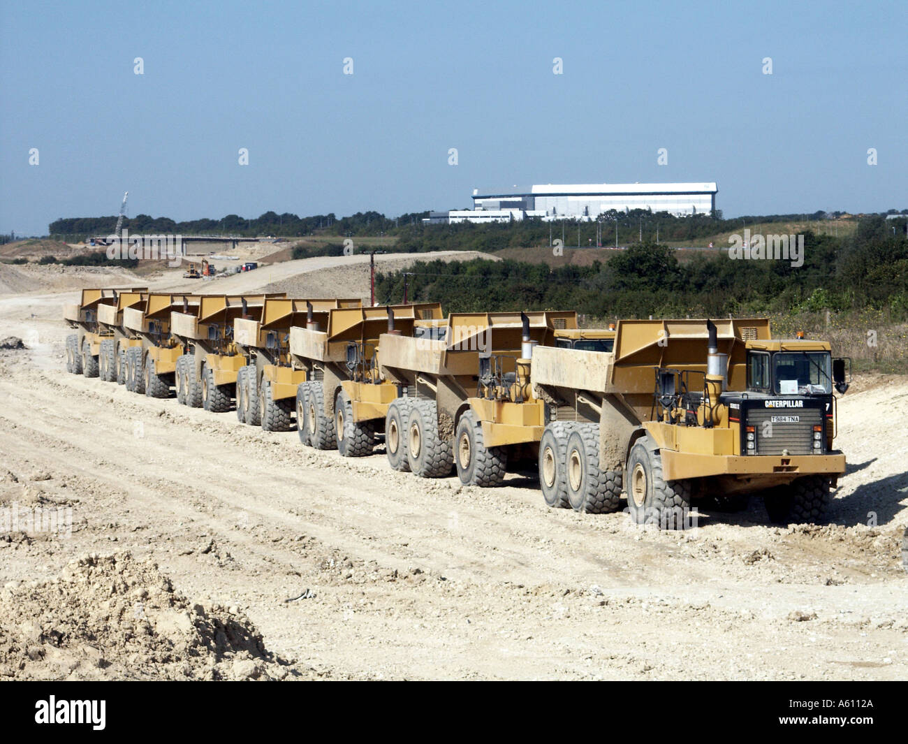 Tombereaux Caterpillar sept en longue file sur un nouveau chantier de construction d'autoroute pour former une route de liaison vers l'aéroport de Stansted près de Takeley dans l'Essex, Angleterre, Royaume-Uni Banque D'Images