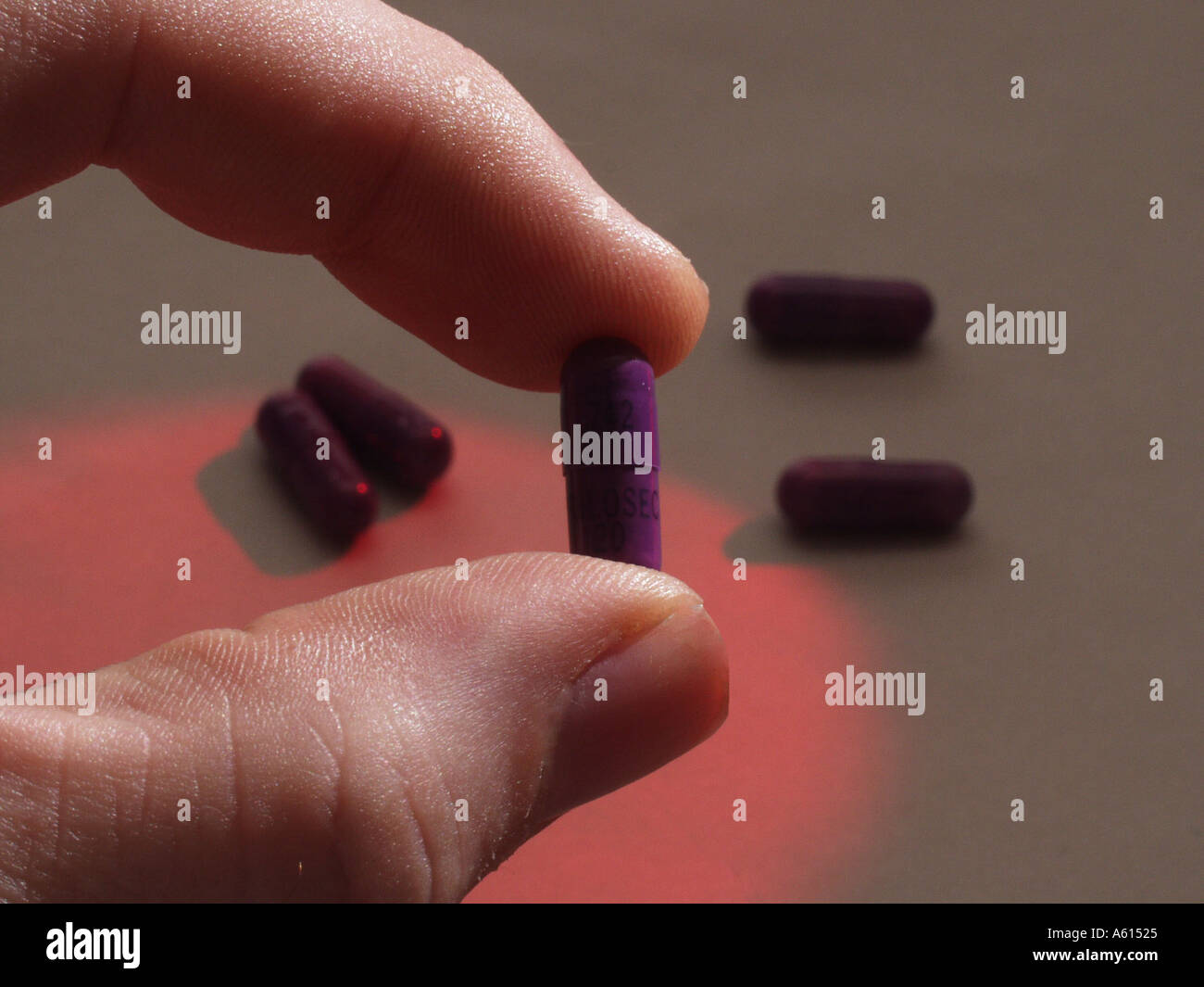 Libre de doigts holding Medicine Capsules de Nexium du flou des pilules dans l'arrière-plan Banque D'Images
