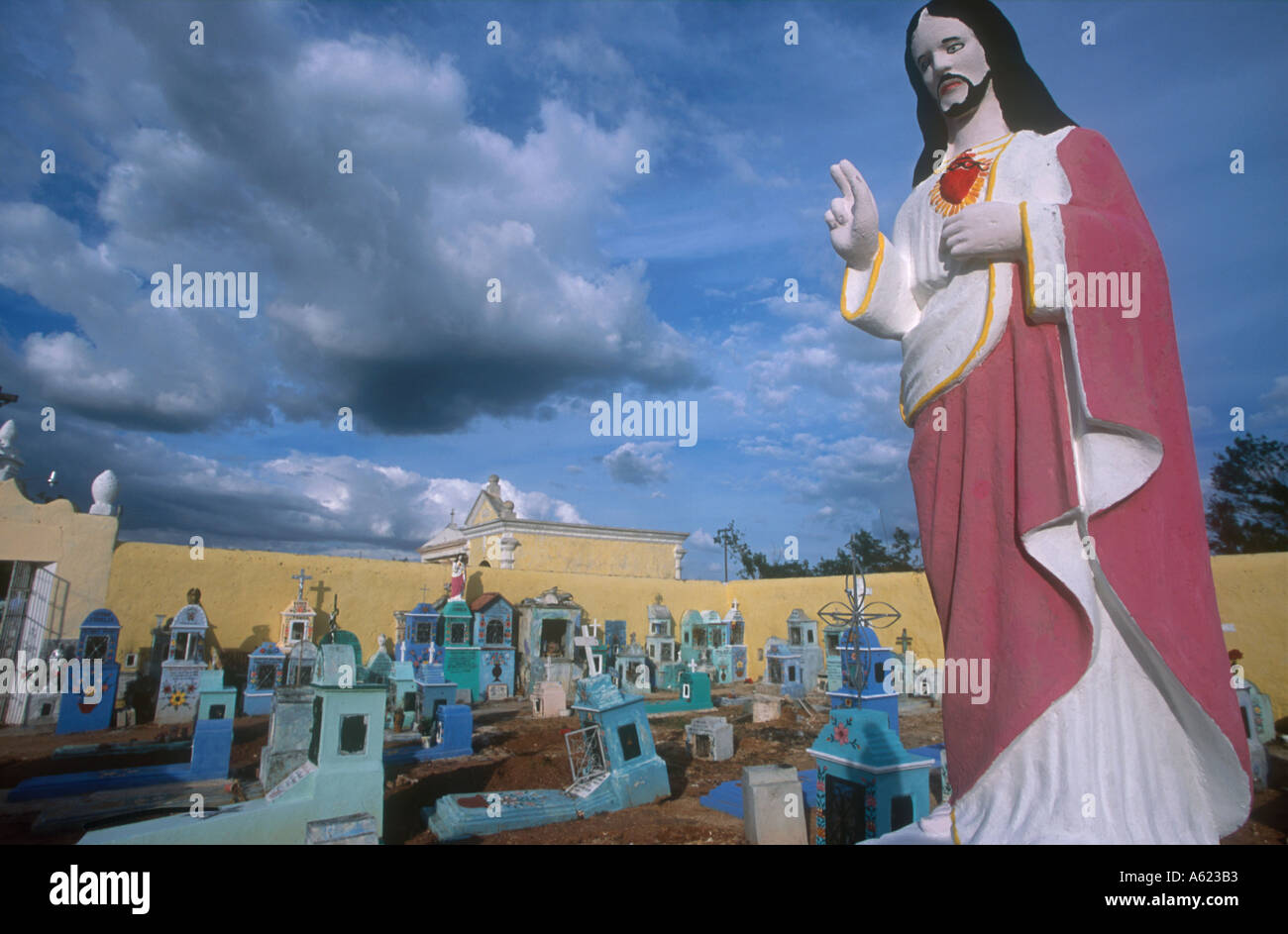 Yucatan Mexique Hoctun cimetière avec religieux peint statue de Jésus Christ en premier plan et des tombes peintes en bleu et turquoise Banque D'Images