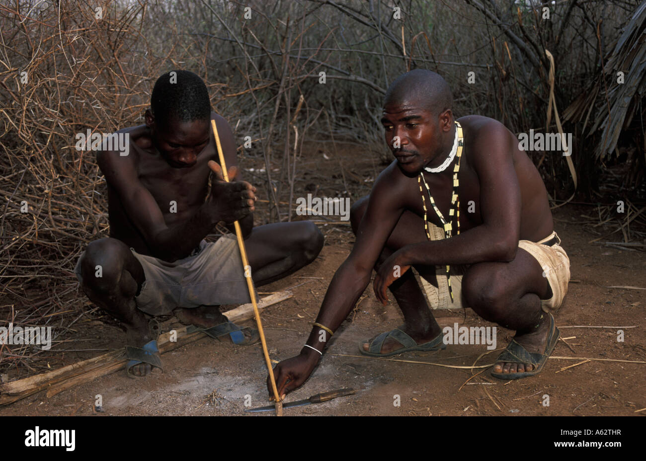 Hadza man making un feu avec un bâton et stone Lake Eyasi Tanzanie petite tribu de chasseurs-cueilleurs Banque D'Images