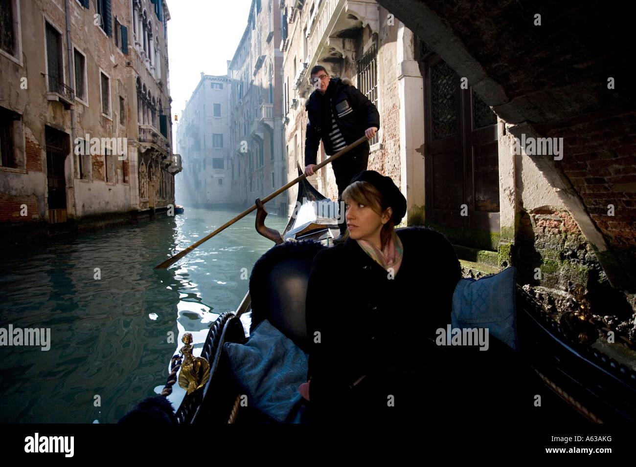 Une femme prend un tour sur une gondole en février à travers les canaux de Venise Italie Banque D'Images
