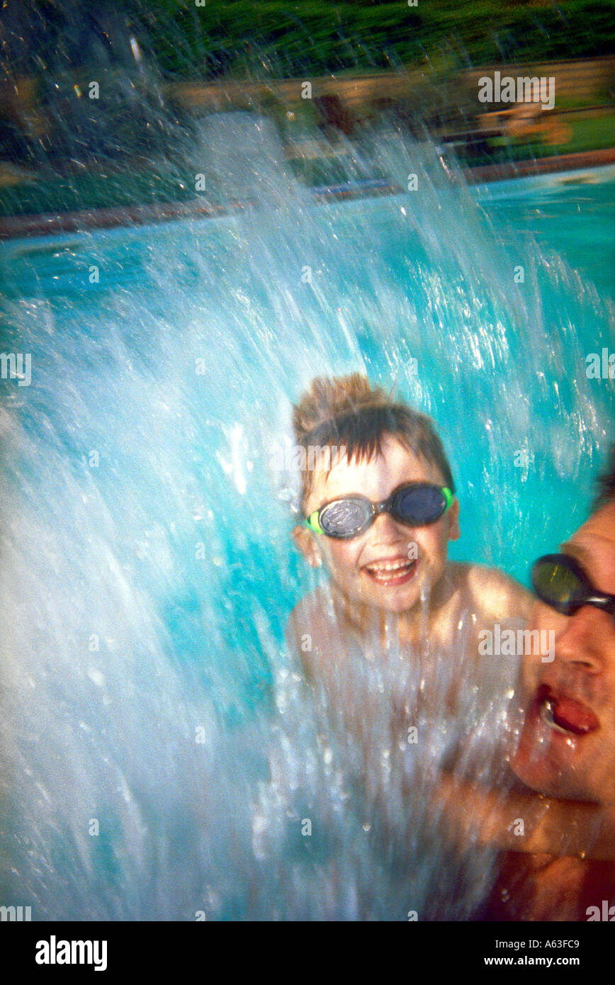 L'homme et jeune garçon jumping into swimming pool Banque D'Images