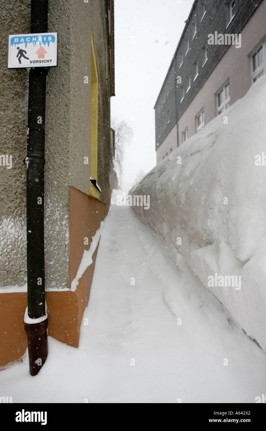 Danger de la glace sur une maison à toit de signer à côté d'un petit chemin enneigé à très élevé dans la neige Oberwiesenthal, Erzgebirge Banque D'Images