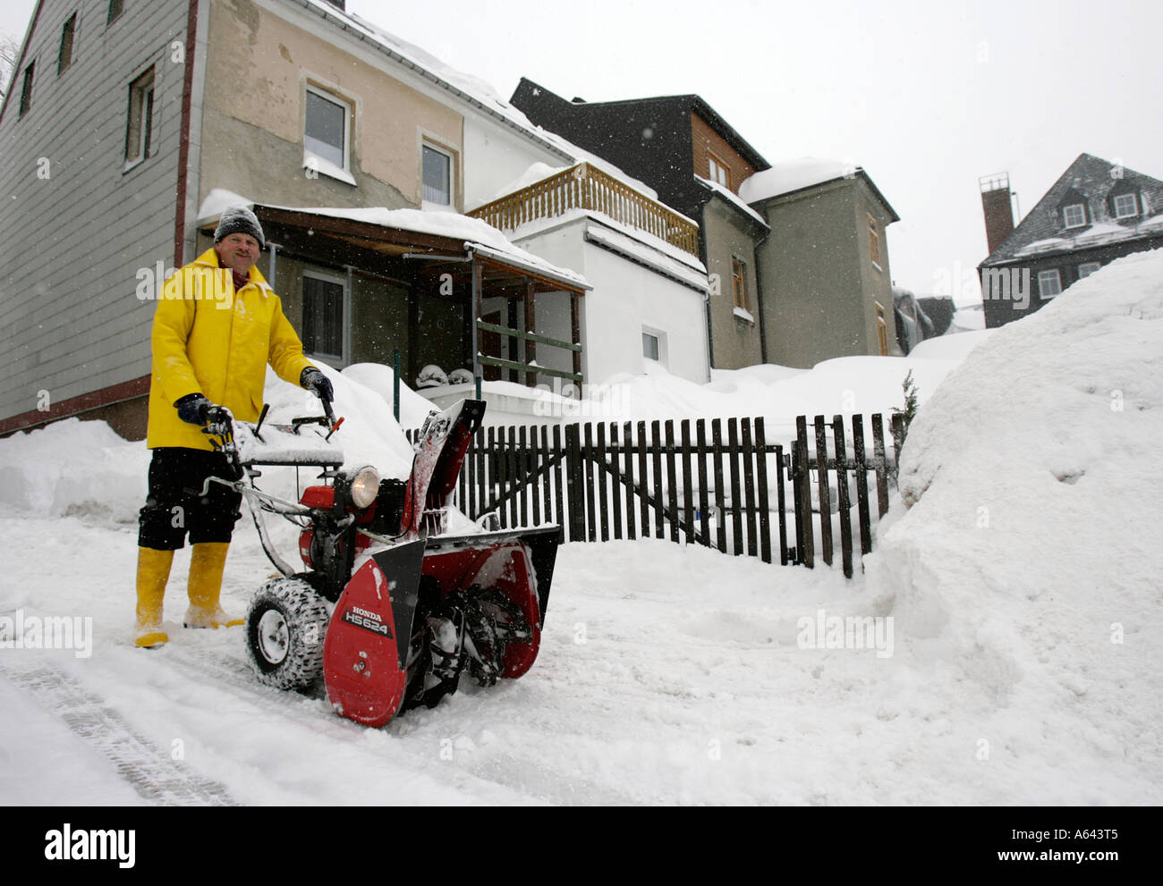 L'homme se déplace de la neige à l'aide d'une clôture de jardin souffleuse automatique à Oberwiesenthal, Erzgebirge, Saxe, Erz Monts Métallifères Banque D'Images