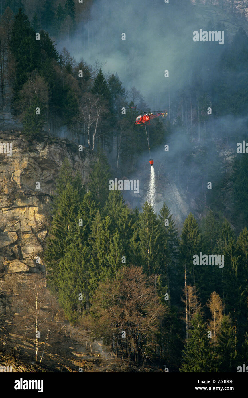 La chute de l'hélicoptère de l'eau sur feu de forêt près du village de la vallée de verzasca sonogno alpes Suisse canton du Tessin suisse Banque D'Images