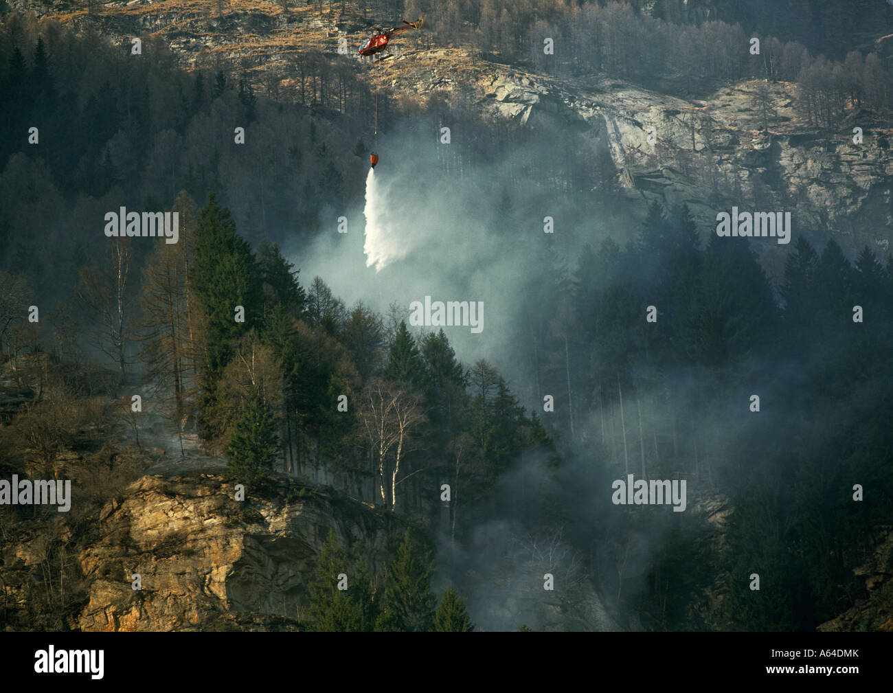 La chute de l'hélicoptère de l'eau sur feu de forêt près du village de la vallée de verzasca sonogno alpes Suisse canton du Tessin suisse Banque D'Images