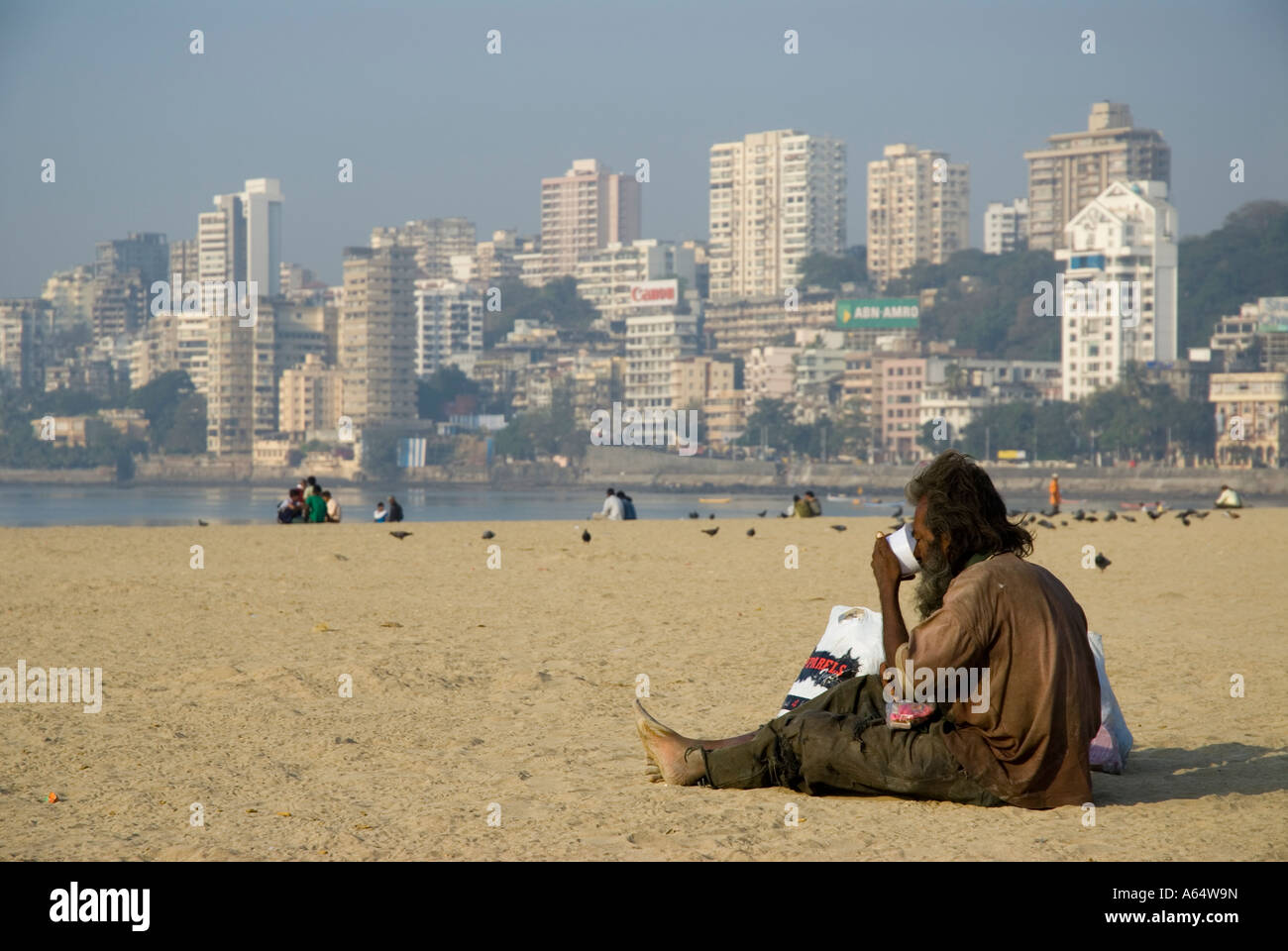 Un sans-abri sur la plage de Chowpatty Mumbai Inde avec appartements et gratte-ciel en arrière-plan Banque D'Images