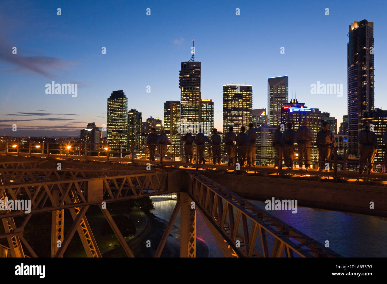 Un groupe de grimpeurs sur Brisbane's Story Bridge sont découpé sur la ville illuminée skyline Banque D'Images