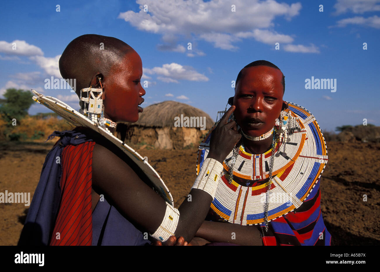 Les femmes masaï peindre leurs visages d'ocre rouge en préparation d'une cérémonie Longido Tanzanie Banque D'Images