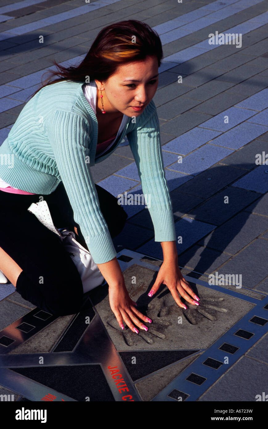 Une femme met ses mains dans les empreintes de Jackie Chan à Hong Kong's Avenue of the Stars Banque D'Images