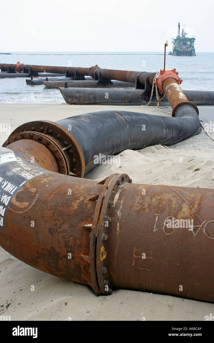 Navire et gros tuyau métallique pour sucer et verser du sable sur la plage  Photo Stock - Alamy
