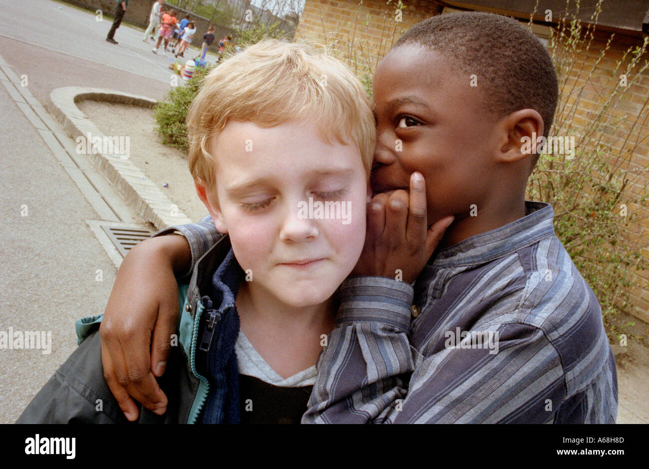 Deux garçons whispering a secret à l'autre à la pause à l'école primaire. Banque D'Images