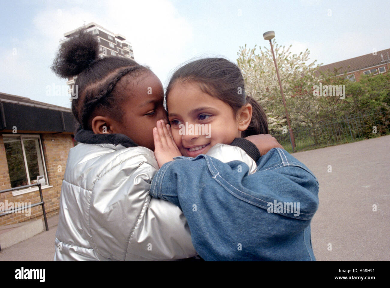 Deux filles whispering a secret à l'autre à la pause à l'école primaire. Banque D'Images