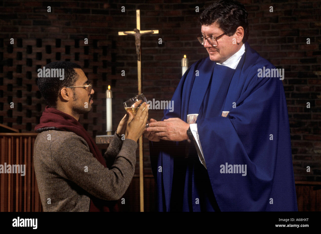 Prêtre distribue la communion à parishiner vin lors de la communion de masse Banque D'Images