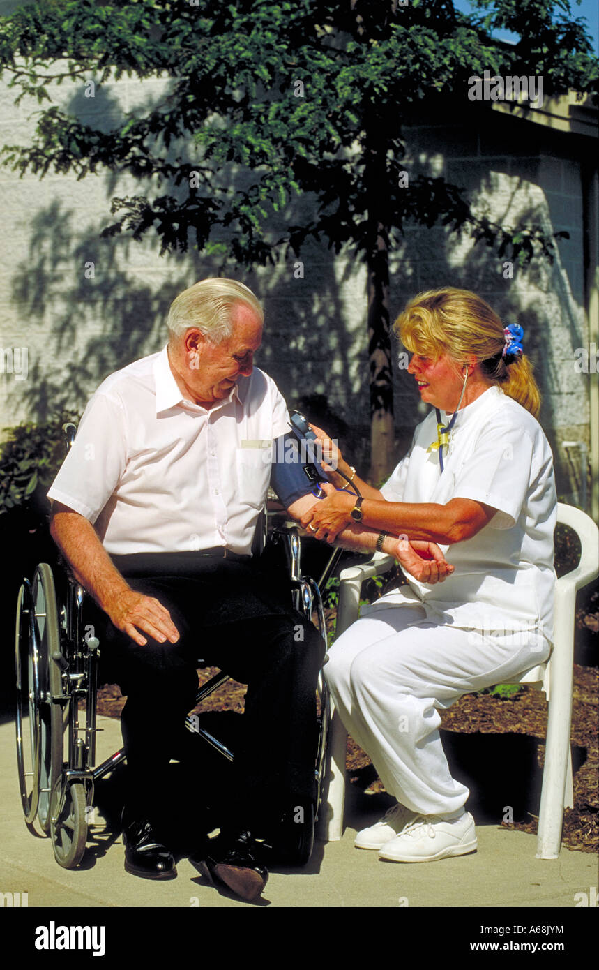 La pression artérielle est infirmière d'un homme âgé en fauteuil roulant Banque D'Images
