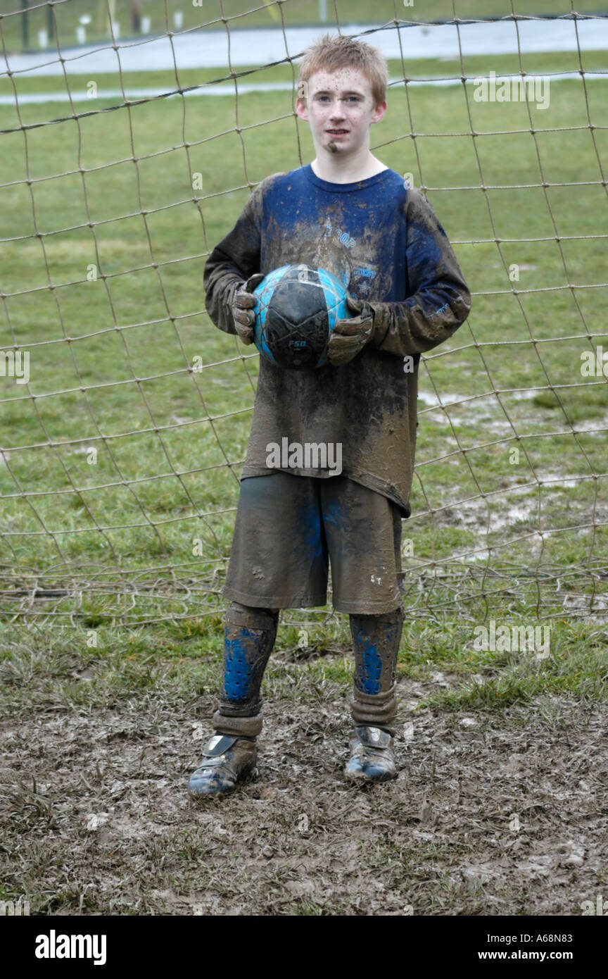 Très boueux teenage boy après avoir joué au soccer dans le gardien de la pluie Banque D'Images