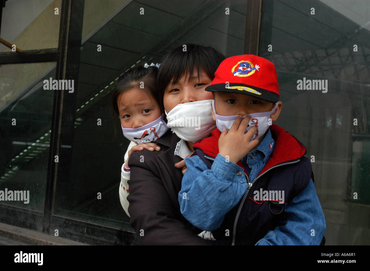 Une femme migrante et son fils et sa fille tous les masques d'attendre à quitter Pékin après l'éclosion de SRAS a Banque D'Images