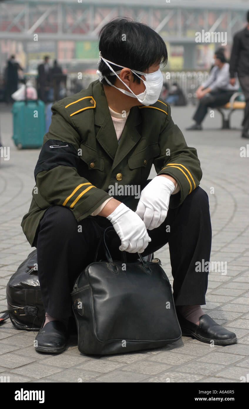 Un travailleur migrant avec deux masques attendre à quitter Pékin après l'éclosion de SRAS a Banque D'Images
