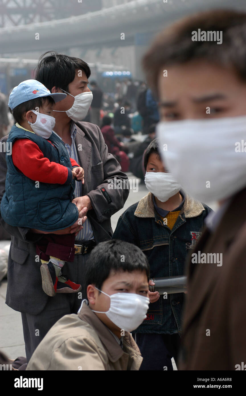 Les travailleurs migrants avec les masques d'attendre à quitter Pékin après l'éclosion de SRAS a Banque D'Images