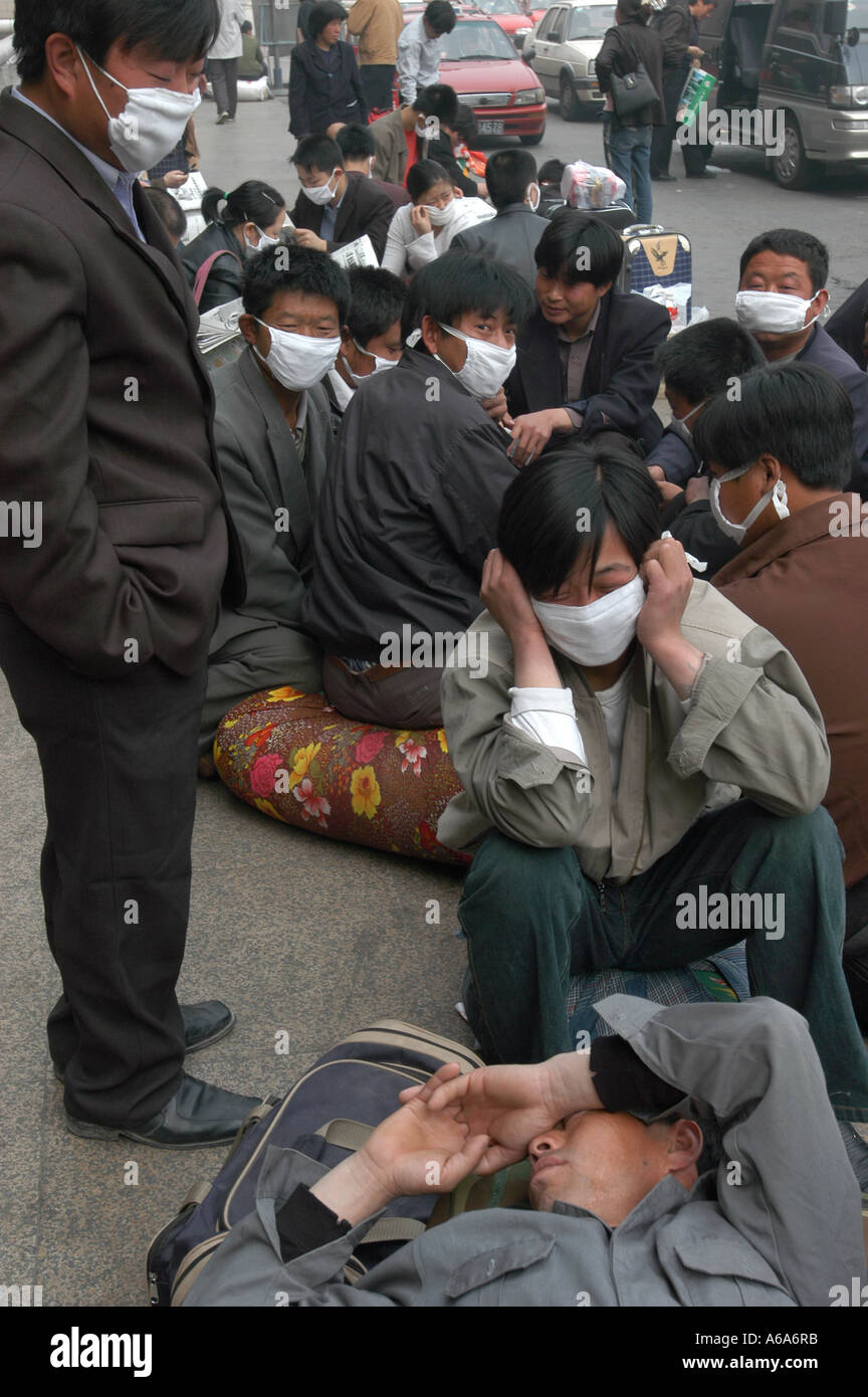 Les travailleurs migrants avec les masques d'attendre à quitter Pékin après l'éclosion de SRAS. 25-Apr-2003 Banque D'Images