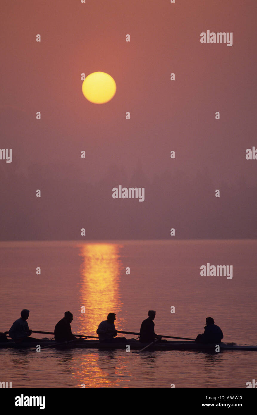 Équipage sur Union Bay silhoueté au lever du soleil avec des oars dans l'eau, réflexions Seattle Washington USA Banque D'Images