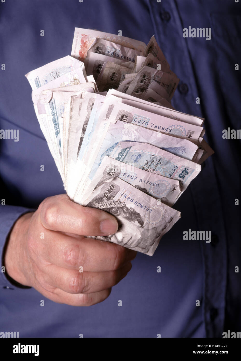 Homme d'affaires gros plan saisissant la main et tenant sur des piles d'espèces mélangées dans des billets de banque monétaires en livre sterling posés par le modèle Angleterre Royaume-Uni Banque D'Images