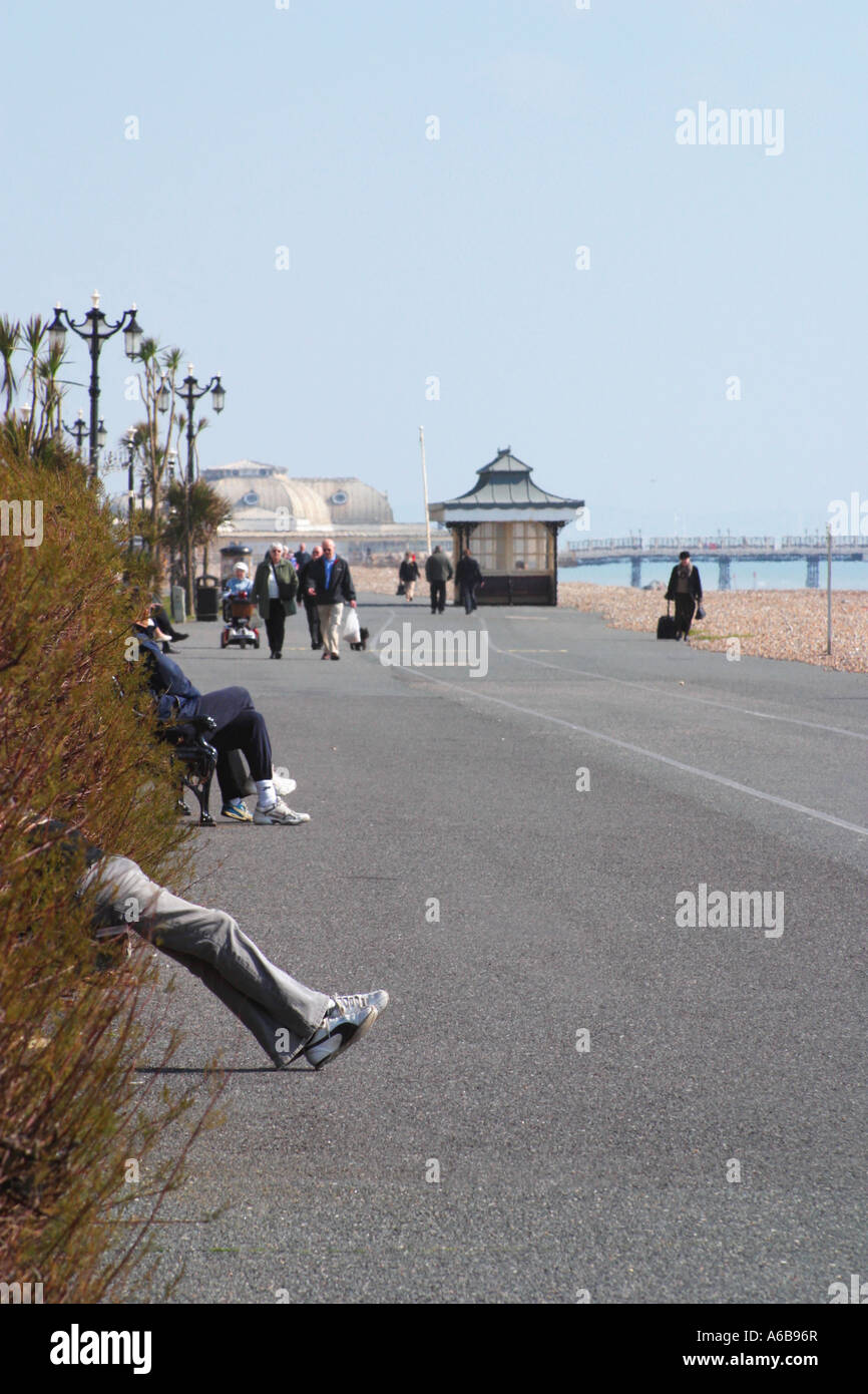 Vacanciers assis le long de la promenade sur le front de mer de Worthing, West Sussex, Royaume-Uni Banque D'Images