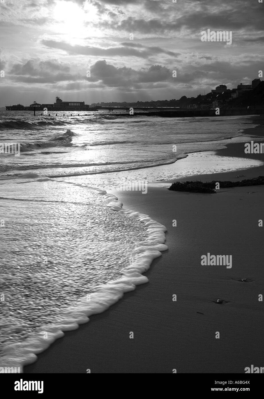 La plage et la jetée de Bournemouth dans le soleil du soir en noir et blanc Banque D'Images