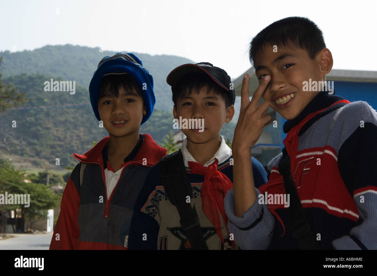 Trois écoles enfants sur leur chemin de retour s'arrêter pour discuter avec les touristes sur l'Ile de Cat Ba Vietnam du Nord Banque D'Images