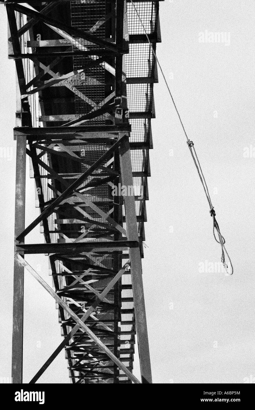 Potence. Une des balançoires corde sinistrement dans le vent d'une rivière convoyeur. Converti à l'image monochrome avec ajout de grain. Banque D'Images