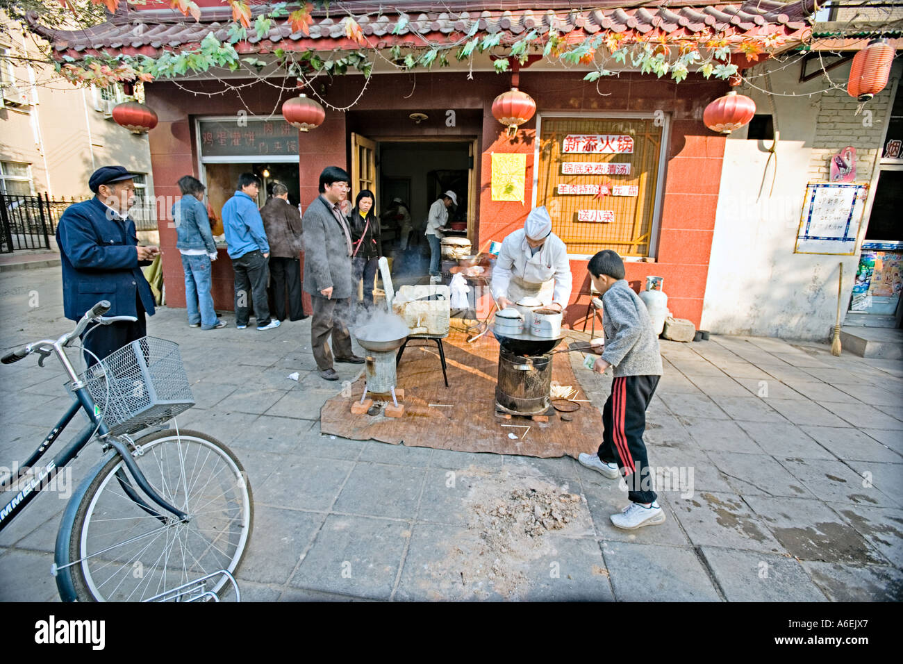 Chine Pékin petit mais occupé restaurant du quartier avec des chefs mis en place sur le trottoir pour préparer le petit déjeuner quenelles Banque D'Images