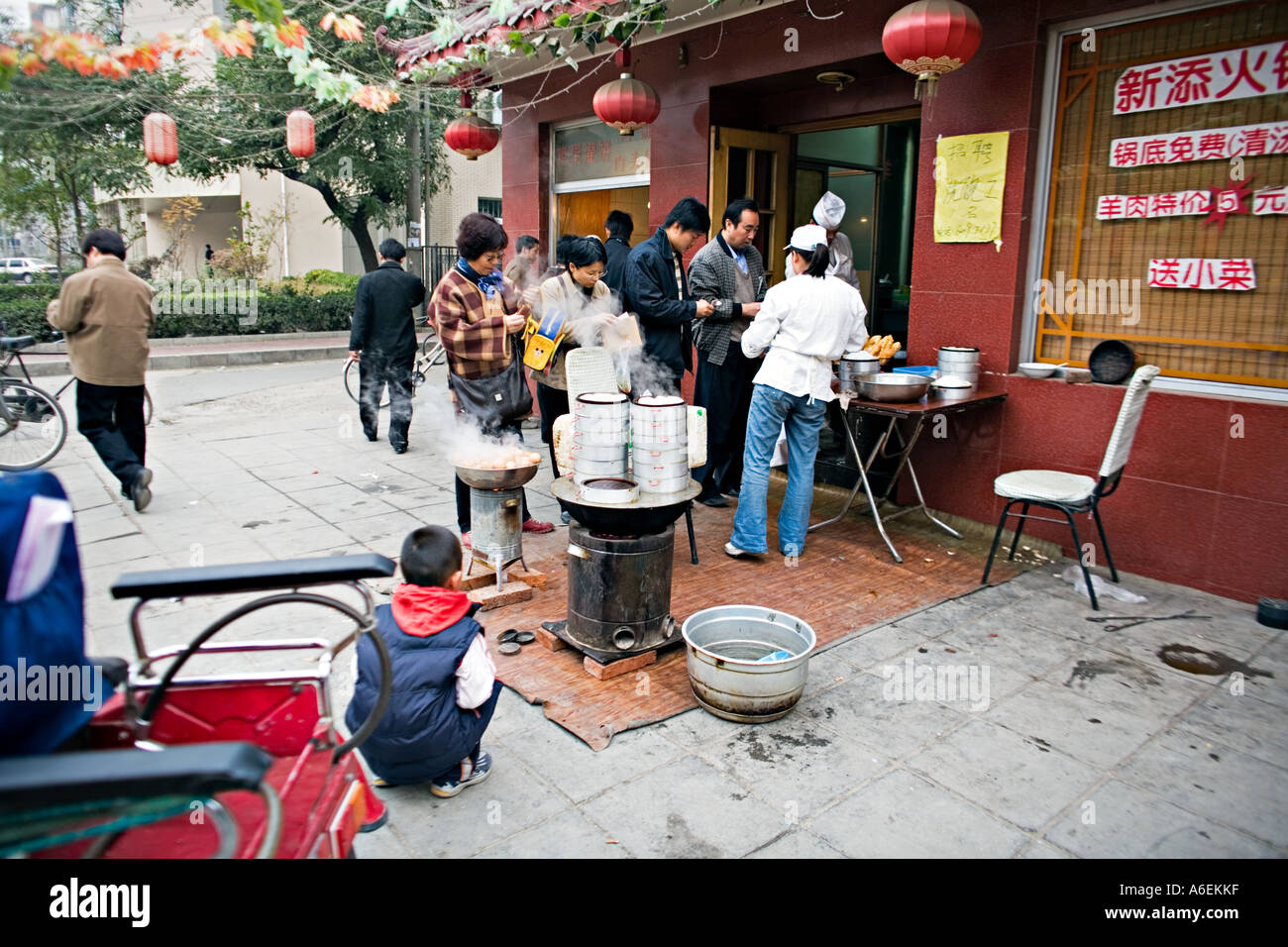 Chine Pékin petit mais occupé restaurant du quartier avec des chefs mis en place sur le trottoir pour préparer le petit déjeuner œufs durs quenelles Banque D'Images