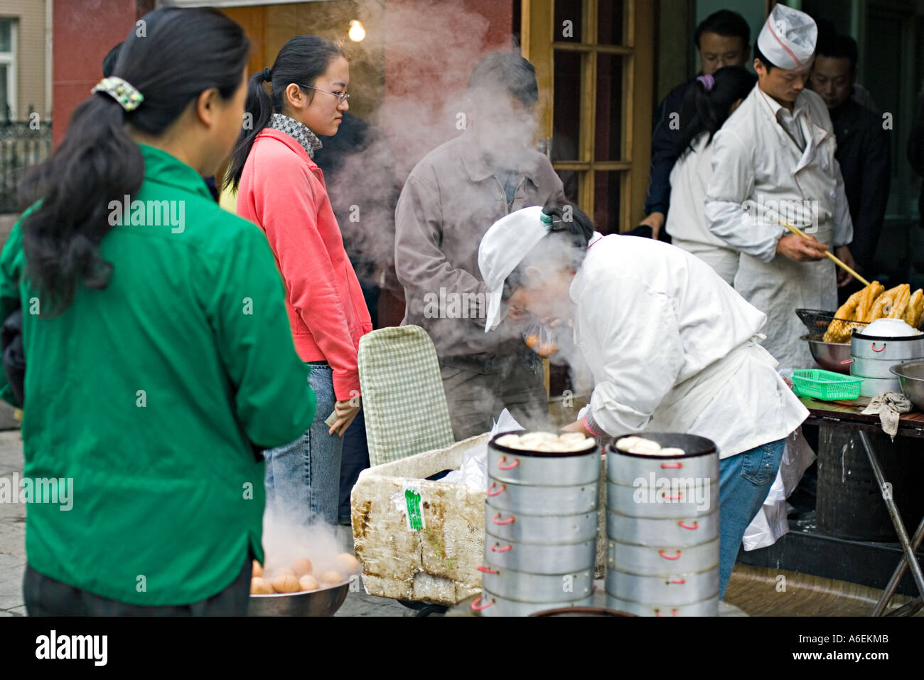 Chine Pékin petit mais occupé restaurant du quartier avec des chefs mis en place sur le trottoir pour préparer le petit déjeuner œufs durs quenelles Banque D'Images