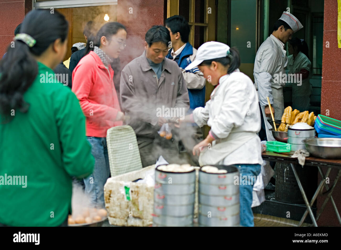 Chine Pékin petit mais occupé restaurant du quartier avec des chefs mis en place sur le trottoir pour préparer le petit déjeuner œufs durs quenelles Banque D'Images