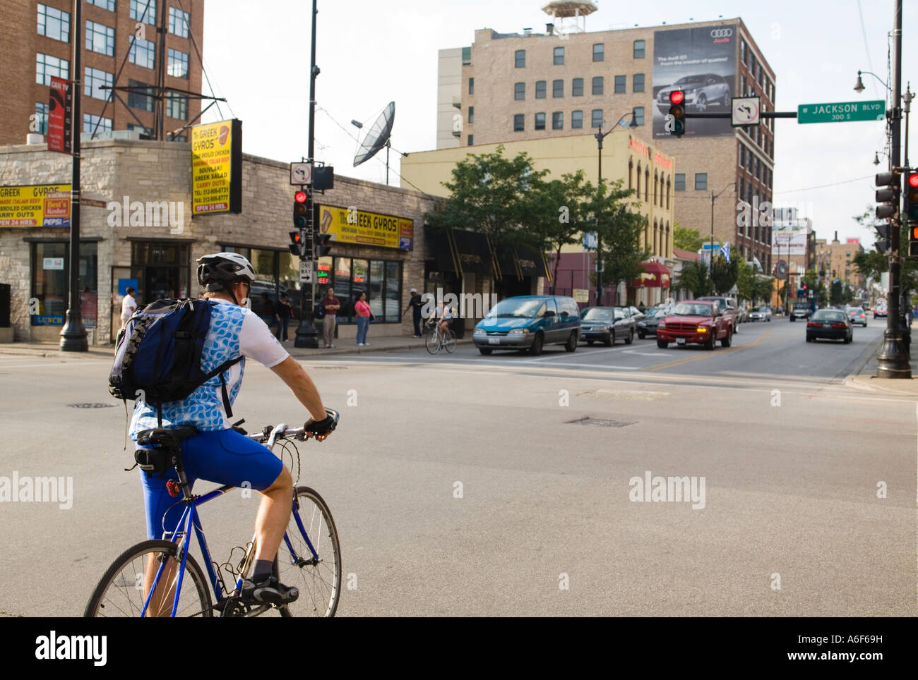 Dans Bicylists Chicago Illinois bike lane Jackson Boulevard et Halsted street intersection homme cycliste avec sac à dos Banque D'Images