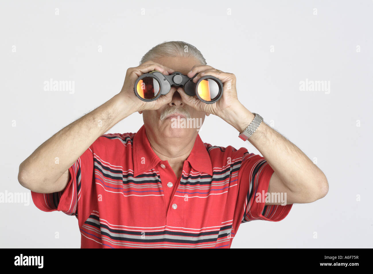 Old Man looking through binoculars Senior citizen old man wearing red T Shirt gris avec des bandes noires et blanches MR 703B Banque D'Images