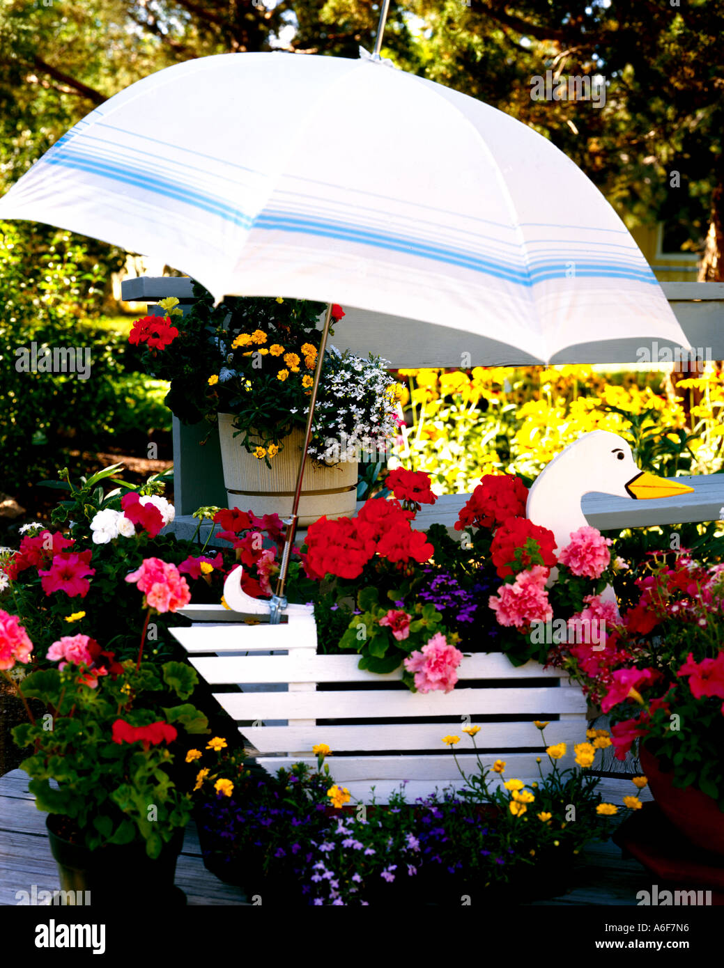 Fleurs d'été sur le jardin doté d''un semoir en forme d'oie à l'ombre d'un parapluie Banque D'Images